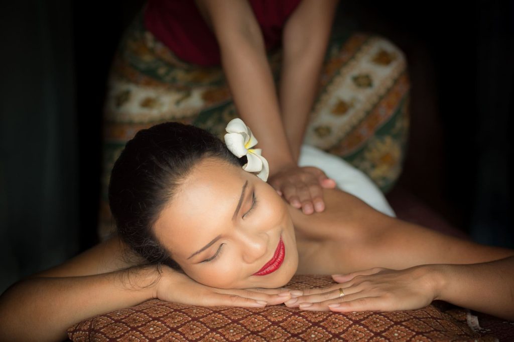 Femme asiatique allongée sur le ventre qui se fait masser par une femme dans un décor thaïlandais