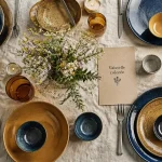 Vaisselle coloré : assiettes en grès émaillé bleu et ocre sur table vivante